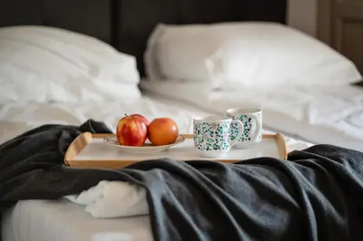 a tray with two cups and apples on a bed at Wroblewskiego No 4 Residence in Kraków