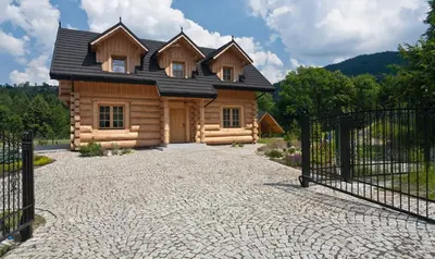 a log cabin with a black roof and a gate at Gorczański Domek - Koninki in Poręba Wielka