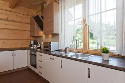 a kitchen with white cabinets and a large window at Gorczański Domek - Koninki in Poręba Wielka