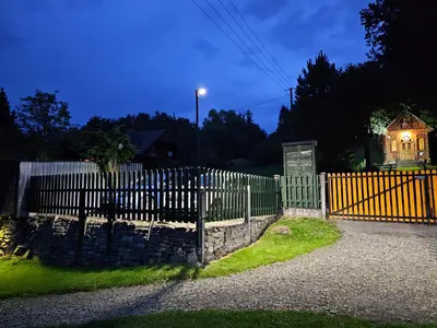 a fence in front of a house with a light at Domki Mosorczyk in Zawoja