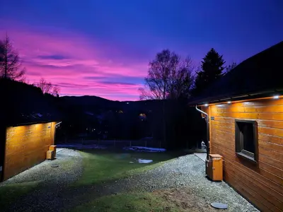 a building with a sunset in the background at Domki Mosorczyk in Zawoja