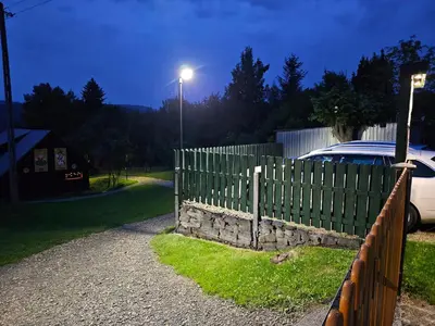 a fence and a car parked next to a street light at Domki Mosorczyk in Zawoja