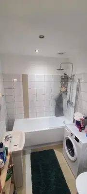 a bathroom with a white tub and a washing machine at The Augustianska Getaway in Kraków
