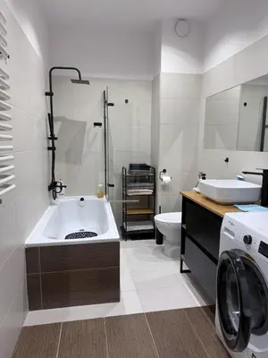a bathroom with a tub and a washing machine at Płaszowska Apartments in Kraków