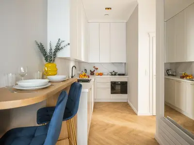 a kitchen with white cabinets and blue chairs at Astor Residence - Fragola Apartments in Kraków