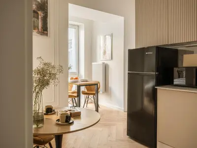 a kitchen with a table and a stainless steel refrigerator at Astor Residence - Fragola Apartments in Kraków