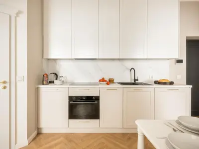 a white kitchen with white cabinets and a sink at Astor Residence - Fragola Apartments in Kraków