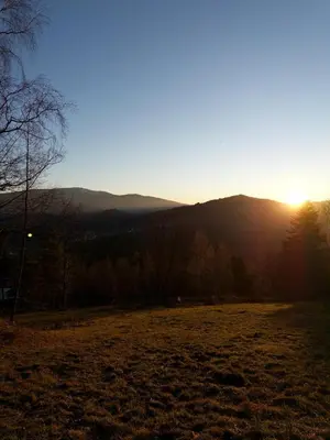 a field with the sun setting in the mountains at Blejkówka in Stryszawa
