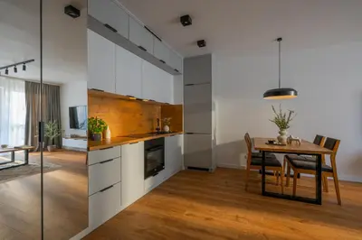 a kitchen with white cabinets and a table and a dining room at Apartamenty w centrum Krakowa, parking w cenie in Kraków