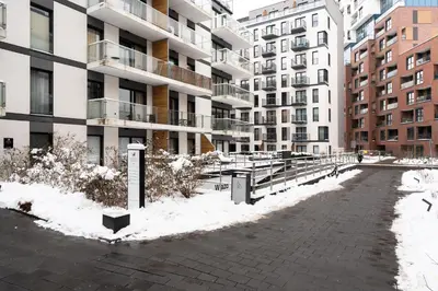 a snow covered street in front of a building at Rakowicka Suite & Parking by Downtown Apartments in Kraków