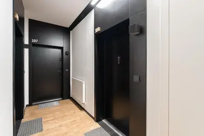 a hallway with black doors and a wooden floor at Rakowicka Suite & Parking by Downtown Apartments in Kraków