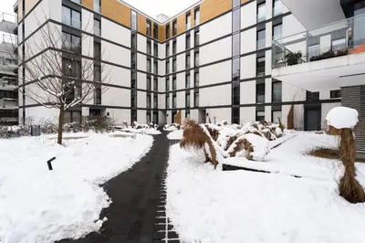 a snow covered sidewalk in front of a building at Rakowicka Suite & Parking by Downtown Apartments in Kraków