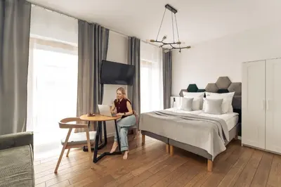 a woman sitting at a table in a bedroom at Rakowicka Suite & Parking by Downtown Apartments in Kraków