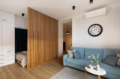a living room with a blue couch and a clock on the wall at Rakowicka Suite & Parking by Downtown Apartments in Kraków