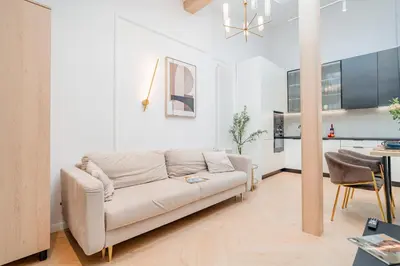 a living room with a white couch and a kitchen at Strzelecka Boutique Apartments in Kraków
