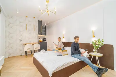 a man and a woman sitting on a bed in a room at Strzelecka Boutique Apartments in Kraków