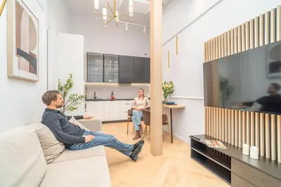 two men sitting on a couch in a living room with a tv at Strzelecka Boutique Apartments in Kraków