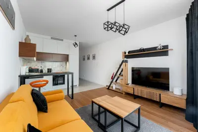 a living room with a yellow couch and a tv at Wiślane Tarasy 2 0 Modern Space Studio by BookingHost in Kraków