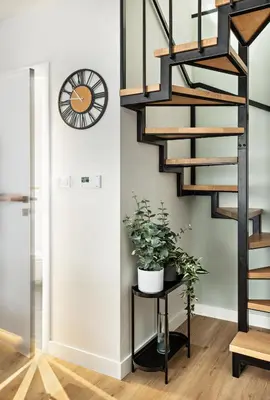 a staircase in a living room with a plant on a table at Berka 12 - Quiet Two-Level Apartment in Kraków