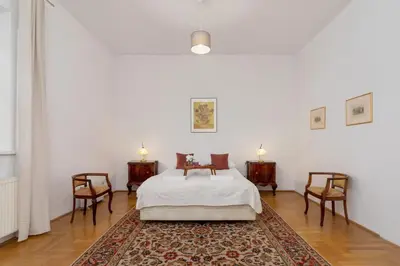 a bedroom with a bed with two chairs and a rug at Heart of the City Apartments Market Square Cracow by Noclegi Renters in Kraków