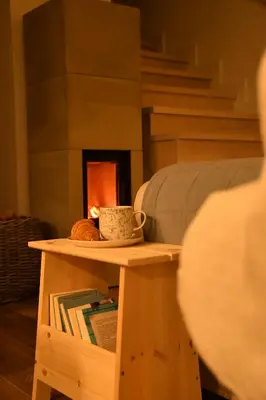 a table with a book shelf and a fireplace at Hygge Beskid in Lachowice