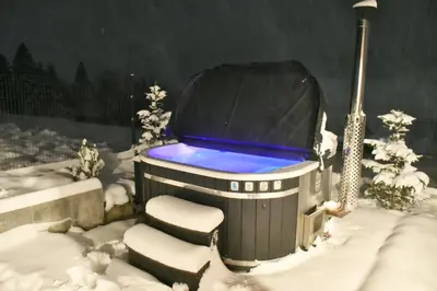 a snow covered hot tub with a chair and a light at Hygge Beskid in Lachowice