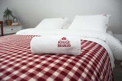 a white bed with a red and white blanket at Hygge Beskid in Lachowice