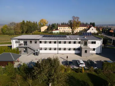 an overhead view of a large white building with a parking lot at Kwatery Smroków in Smroków