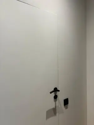 a white wall with a black lamp on it at Cozy Studio near Central Station Krakow in Kraków