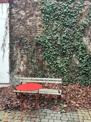 a bench with a red table in front of a wall at Cozy Studio near Central Station Krakow in Kraków
