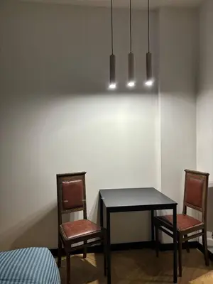 a dining room table with two chairs and two lights at Cozy Studio near Central Station Krakow in Kraków