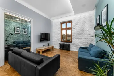 a living room with a black couch and blue chairs at Świętej Gertrudy Chic Apartment by BookingHost in Kraków