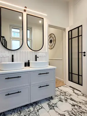 a white bathroom with two sinks and two mirrors at Apartament Krak Number One in Kraków