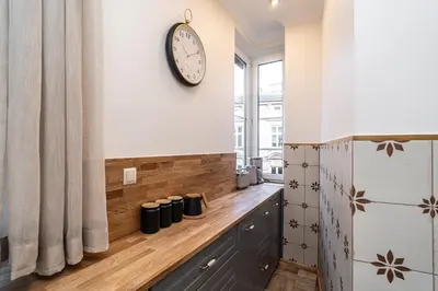 a clock on a wall next to a counter with cups at RentPlanet - Apartament Sobieskiego in Kraków