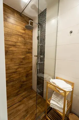 a bathroom with a shower with a wooden wall at Central Kazimierz Apartment in Kraków
