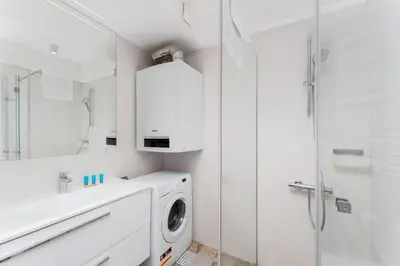 a white bathroom with a washing machine and a mirror at Starowiślna 14 Downtown Studios by BookingHost in Kraków