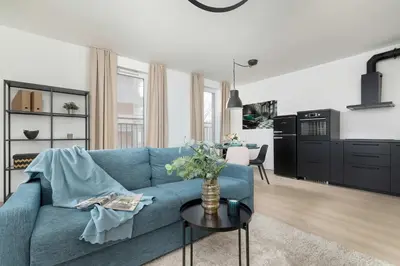 a living room with a blue couch and a table at Elegant Apartment Zbożowa in Kraków with Parking by Noclegi Renters in Kraków