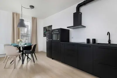 a kitchen with black cabinets and a table with chairs at Elegant Apartment Zbożowa in Kraków with Parking by Noclegi Renters in Kraków