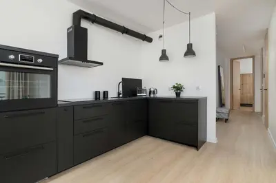 a kitchen with black cabinets and black appliances at Elegant Apartment Zbożowa in Kraków with Parking by Noclegi Renters in Kraków