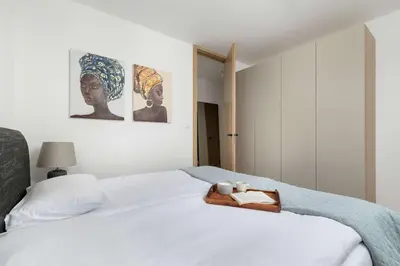 a bedroom with a white bed with a wooden tray on it at Elegant Apartment Zbożowa in Kraków with Parking by Noclegi Renters in Kraków