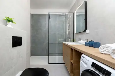 a bathroom with a shower and a washing machine at Elegant Apartment Zbożowa in Kraków with Parking by Noclegi Renters in Kraków