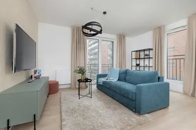 a living room with a blue couch and a tv at Elegant Apartment Zbożowa in Kraków with Parking by Noclegi Renters in Kraków