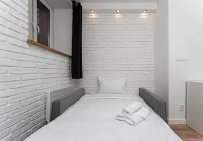 a bed in a room with a brick wall at Traugutta Cozy Studio by BookingHost in Kraków