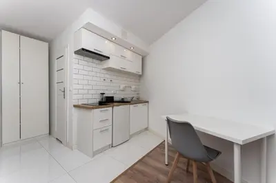 a white kitchen with a desk and a chair at Traugutta Cozy Studio by BookingHost in Kraków