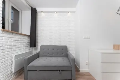 a gray chair in a room with a brick wall at Traugutta Cozy Studio by BookingHost in Kraków
