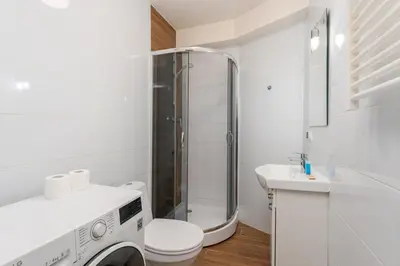a bathroom with a shower and a washing machine at Traugutta Cozy Studio by BookingHost in Kraków