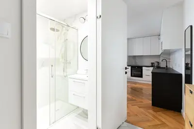 a kitchen with white cabinets and a glass shower at Native Apartments Kościuszki 39I19 in Kraków