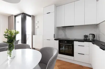 a kitchen with white cabinets and a table and chairs at Native Apartments Kościuszki 39I19 in Kraków