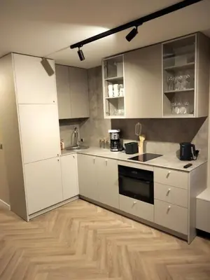 a kitchen with white cabinets and a wooden floor at Way2Stay Kazimierz in Kraków