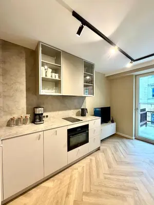 a kitchen with white cabinets and a large window at Way2Stay Kazimierz in Kraków